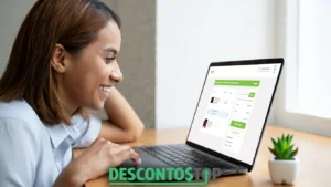 Mulher sorridente usando um notebook sobre uma mesa de madeira, acompanhada de um pequeno vaso de planta. Na tela do computador, aparece uma página de finalização de compra online no site da Acer, exibindo detalhes do pedido e o desconto aplicado. Na parte inferior da imagem, há o logotipo "DESCONTO TOP".