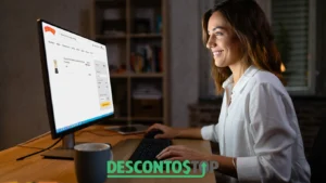 Mulher sorridente usando um computador comprando um conjunto de roupas na Alakazoo, com um produto adicionado ao carrinho. Na parte inferior da imagem, aparece o logo do site Descontos Top.