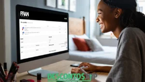 Mulher sorridente usando um computador de mesa enquanto finaliza uma compra online no site da marca FRAN by Franciny Ehlke. Na tela, é possível ver o resumo do pedido com itens de maquiagem, campos para preenchimento de dados pessoais e as opções de pagamento. A cena acontece em um ambiente doméstico, com maquiagens ao fundo.