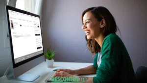 Imagem de uma mulher sorridente olhando para a tela de um computador. Na tela é mostrada o carrinho de compras da loja Hardyn.